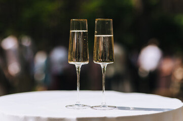 Two glass glasses of champagne are on the table with a white tablecloth.