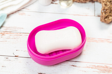soap on pink plastic soap dish with towels on white wooden table in bathroom