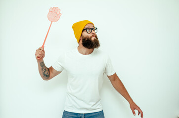 Young caucasian hipster man holding a fly swatter wanting to kill annoying mosquito or a fly.