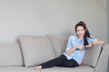 Cute girl asian listening to music on sofa. Relaxation on free time.