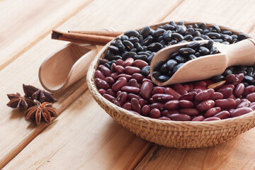 Black beans and red beans in basket on wood background.