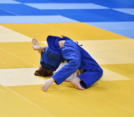 Two Girls judoka in kimono compete on the tatami 