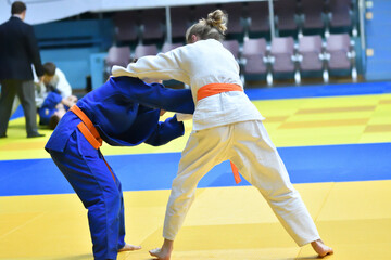 Fototapeta premium Two Girls judoka in kimono compete on the tatami 