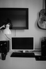 
White computer desk with a monitor, speakers, keyboard, mouse. lamp and guitar, photo in black and...