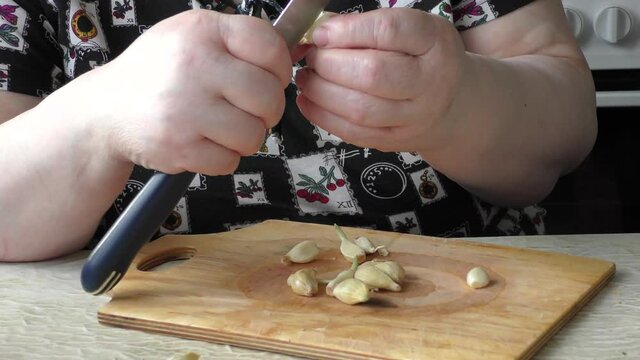 Homemade food preparation process.  The cook cuts the garlic with a knife.  Healthy food concept
