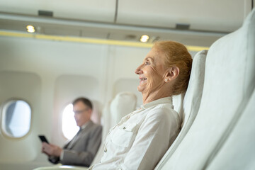 Fototapeta premium Passenger elderly woman seated on the plane in flight,Travel concept.