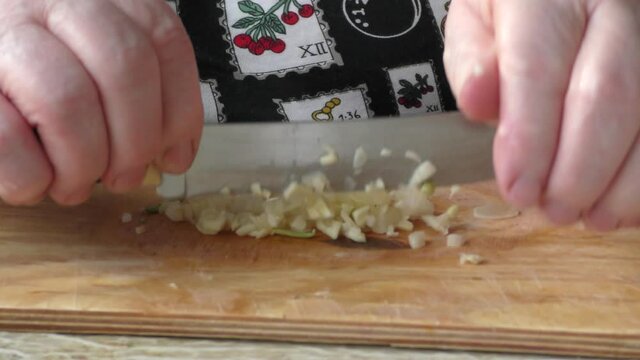 Homemade food preparation process.  The cook cuts the garlic with a knife.  Healthy food concept