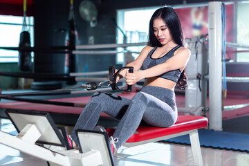 Fototapeta na wymiar Fitness Asian women performing doing exercises training with rowing machine (Seat Cable Rows Machine) in sport gym interior and fitness health club with sports exercise equipment Gym.