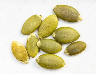 several hulled pumpkin seeds close up on gray