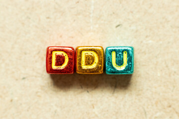 Metallic color alphabet letter block in word DDU (abbreviation of Delivered Duty Unpaid) on wood...