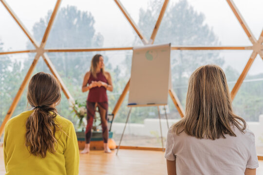 People sitting and listening to trainer near marker board in light room