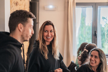 Smiling trainer with long hair speaking to group of people in light room