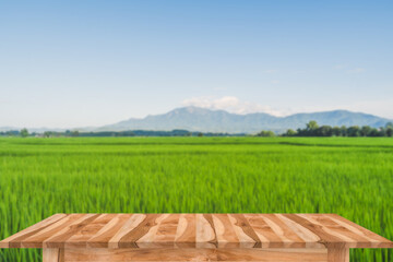 Empty brown wooden table with rice field and blue sky