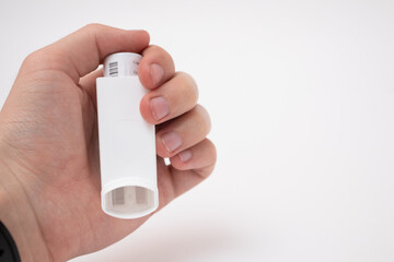Hand holding asthma inhaler on white background - obrazy, fototapety, plakaty