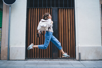 Trendy female with backpack rushing and running on street