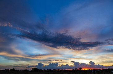 Obraz premium Twilight blue bright and orange yellow dramatic sunset sky in countryside or beach colorful cloudscape texture with white clouds air background.