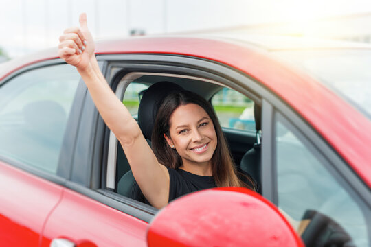 Car. Beautiful woman in the car shows thumbs up. Happy brunette in the car.