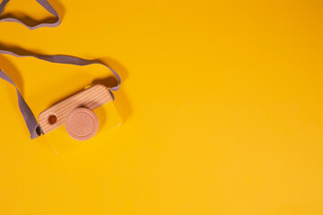 Wooden camera on a yellow background with space for text