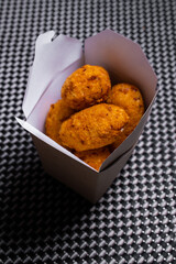 Baked chicken wings with sesame seeds with herbs and sweet sauce in a white box on the table