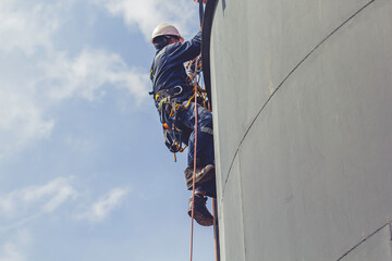 Male worker rope access height safety inspection of thickness storage oil and gas tank