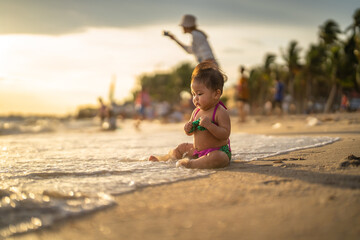 baby in bikini sit on the beach with relaxing and the wind blows in evening time and beautiful sunset light at the beach