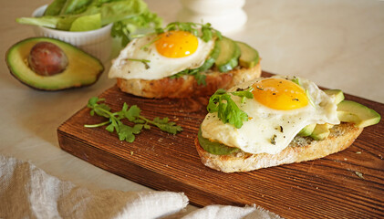sandwich with egg and avocado on a wooden board and one in the background