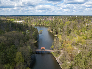 Pedestrian bridge in the park across the river. Aerial drone view.