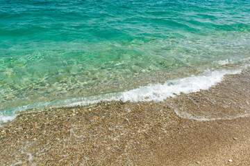 Soft turquoise sea wave on pebble beach. Nature background