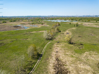 Green meadows on the outskirts of the city in spring. Aerial drone view.