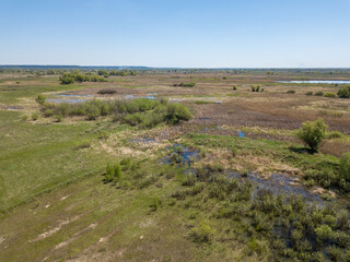 Green meadows on the outskirts of the city in spring. Aerial drone view.