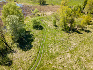 Green meadows on the outskirts of the city in spring. Aerial drone view.