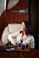 Successful young business woman photographer taking photos with middle format film camera during flight in private plane business jet.