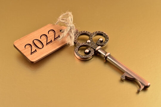2022 New Year Key stock images. Old key with wooden tag 2022. Decorative key isolated on a golden background. Golden New Year 2022. Key with number 2022 stock images