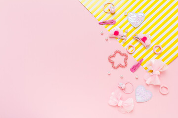 Cute girl's hair accsessories on pink and yellow striped background. Hair clips, hairpins, bow tie on pink background.