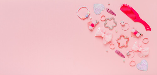 Colorful set of kids accsessories for hairdoes. Hair clips, scrunchies, hairpins, bows, hairbrush for little girls on pink background.