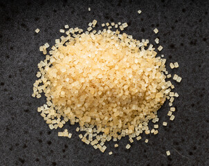 pile of demerara brown cane sugar closeup on black