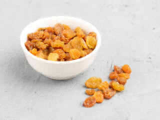 Raisins in a white cup and scattered in a bunch on a gray background, painted with paint on a concrete wall