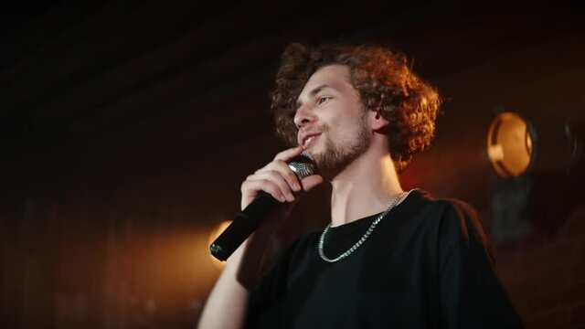 CU PORTRAIT of Young Caucasian male comedian performing his stand-up monologue on a stage of a small venue. Shot with ARRI Alexa Mini LF with 2x anamorphic lens