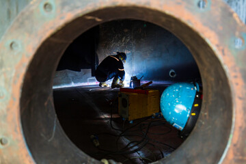 Male worker wearing protective clothing and repair welding sparks industrial construction tank oil...