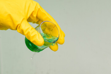 Man in yellow rubber gloves holds a test tube with green liquid. Development of a new drug, chemical experiment. Medical laboratory