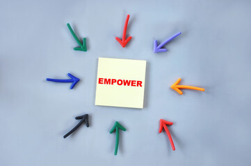 Empower written on yellow sticky note with colorful arrow on grey background. Business synergy concept and agreement together idea