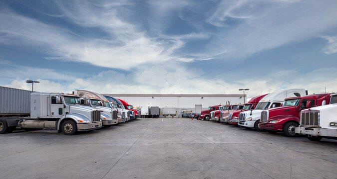 Semi trucks lined up on a parking lot at logistics warehouse