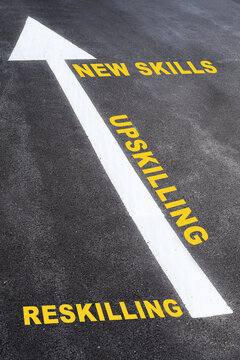 Newskills, upskilling and reskilling with white arrow sign marking on road surface for giving direction. Growth mindset concept and self improvement idea