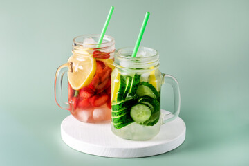Variety of Cold Summer Drinks in Glass Jars Infused Detox Water with Cucumber Lemon and Strawberry Healthy Drink Green Background