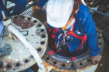Male worker climb inside the stairway storage visual inspection tank into the confined space
