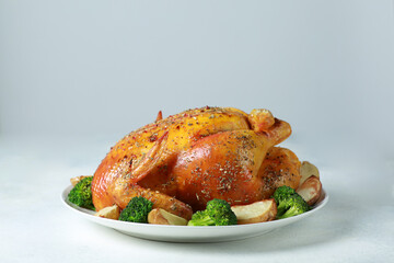 Fried chicken with a golden crust with broccoli and potatoes on a white plate on a white background. Fried poultry with spices and vegetables. Background image for advertising, copy space