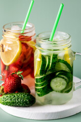 Variety of Cold Summer Drinks in Glass Jars Infused Detox Water with Cucumber Lemon and Strawberry Healthy Drink Green Background Close up
