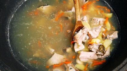 Cooking fish soup in a large pot, outdoors in field conditions. Fishing food. Street kitchen.