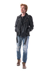 Cool stylish rocker in black leather jacket walking and looking away with hands in pockets. Full body length isolated on white background.