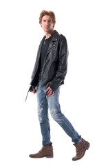 Fototapeta premium Side view of handsome biker or rocker walking and looking behind confident. Full body length isolated on white background.